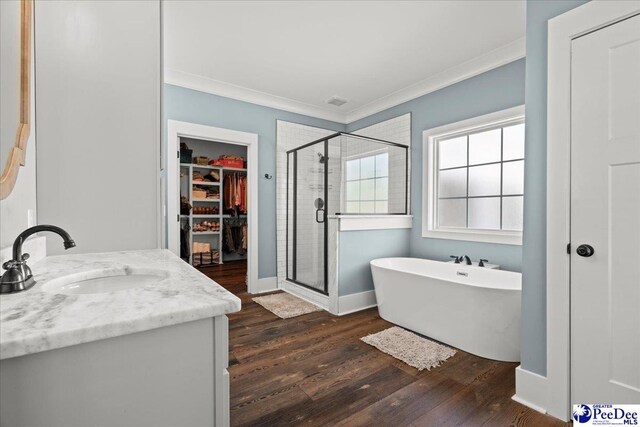 full bath featuring crown molding, wood finished floors, a spacious closet, and a shower stall