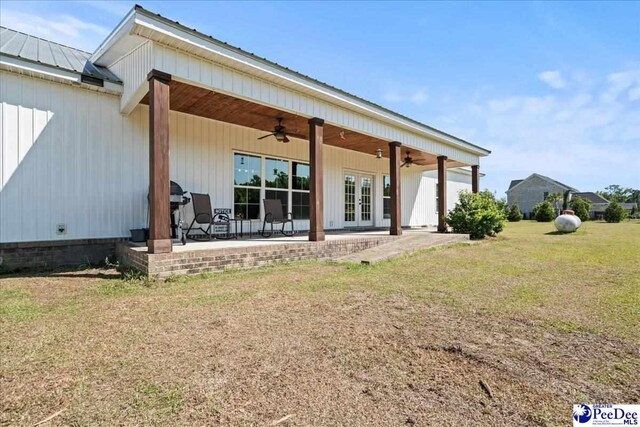 back of house with ceiling fan, french doors, a patio, a yard, and metal roof