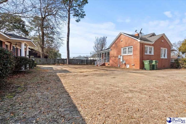 view of property exterior featuring a yard, brick siding, crawl space, and fence