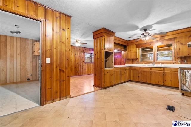 kitchen featuring a wealth of natural light, light countertops, brown cabinets, and wood walls