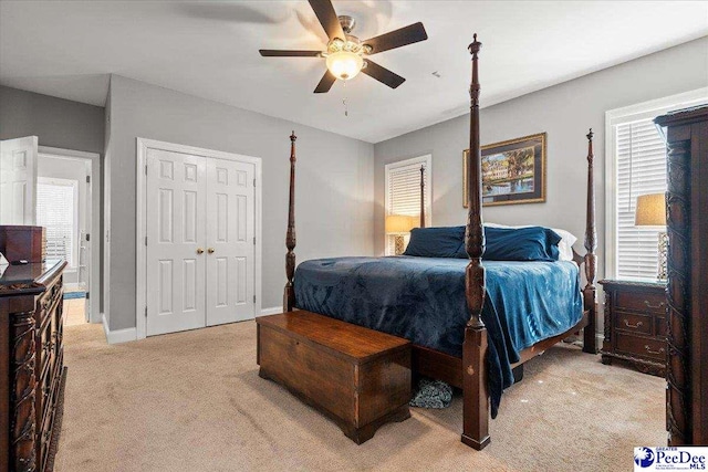 bedroom with a ceiling fan, light colored carpet, baseboards, and a closet