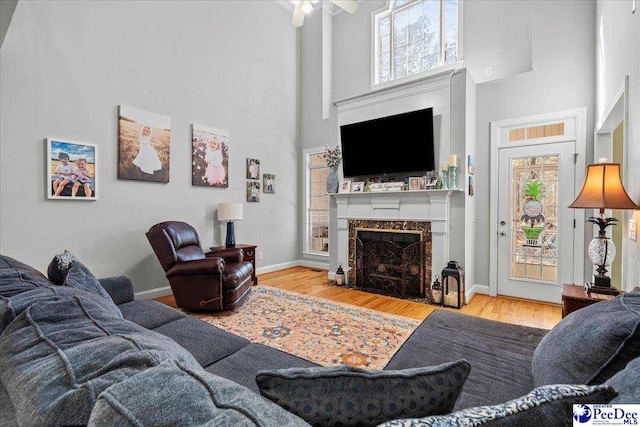 living area with a high ceiling, wood finished floors, baseboards, and a premium fireplace