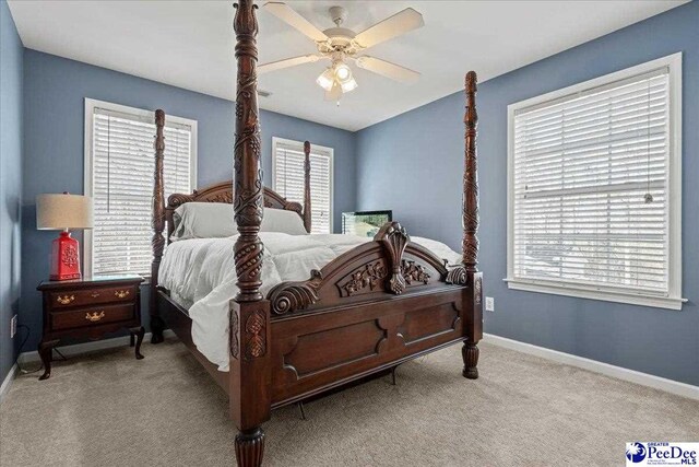 carpeted bedroom featuring multiple windows, a ceiling fan, and baseboards