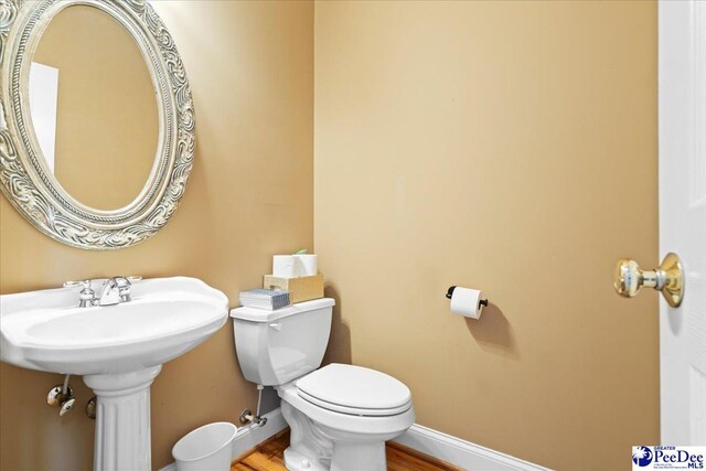 half bath with baseboards and toilet