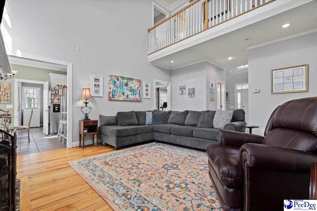 living room with wood finished floors, baseboards, recessed lighting, a towering ceiling, and crown molding