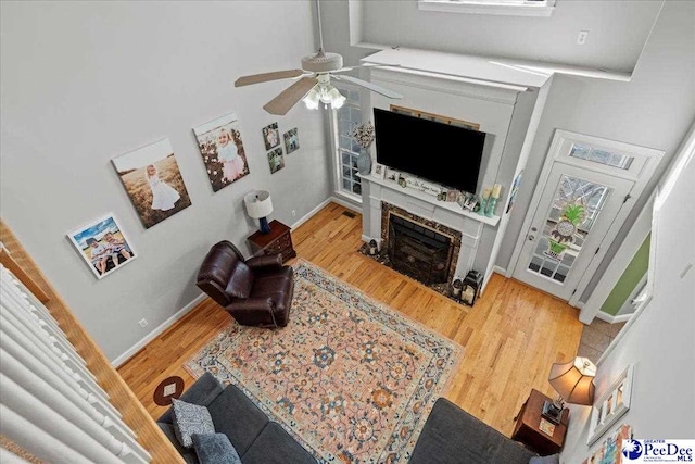 living area featuring a fireplace with flush hearth, baseboards, and wood finished floors