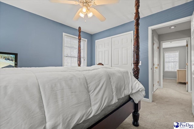 bedroom featuring a ceiling fan, baseboards, a closet, and light carpet