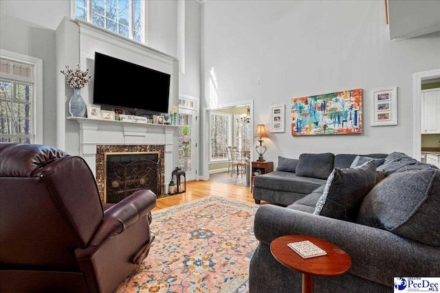 living area with a towering ceiling, wood finished floors, and a high end fireplace