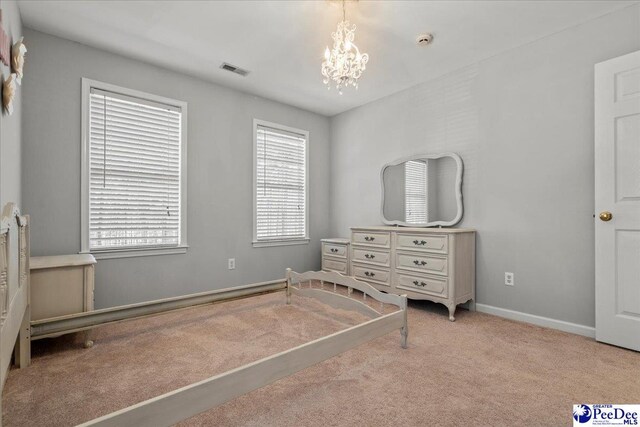 unfurnished bedroom featuring a chandelier, carpet flooring, baseboards, and visible vents