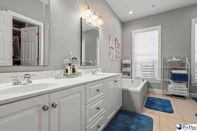 bathroom with tile patterned floors, a bath, double vanity, and a sink