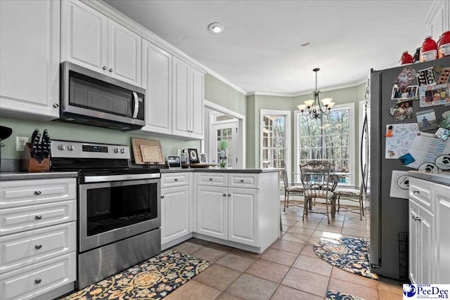 kitchen featuring stainless steel appliances, dark countertops, ornamental molding, and white cabinetry