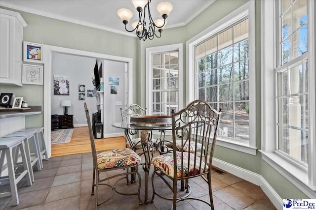 dining area featuring a notable chandelier, a healthy amount of sunlight, baseboards, and ornamental molding