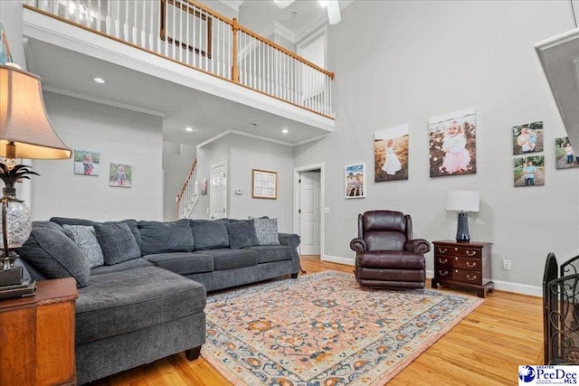 living area featuring ornamental molding, baseboards, and wood finished floors