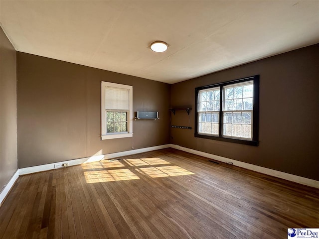 spare room with an AC wall unit and light wood-type flooring