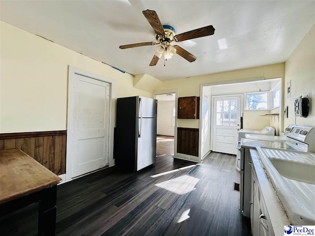 kitchen with sink, wood walls, stainless steel refrigerator, dark hardwood / wood-style floors, and ceiling fan