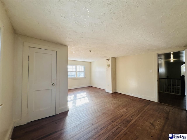 unfurnished room with dark hardwood / wood-style floors and a textured ceiling