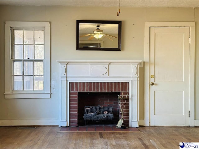 interior details featuring hardwood / wood-style floors, a brick fireplace, and ceiling fan