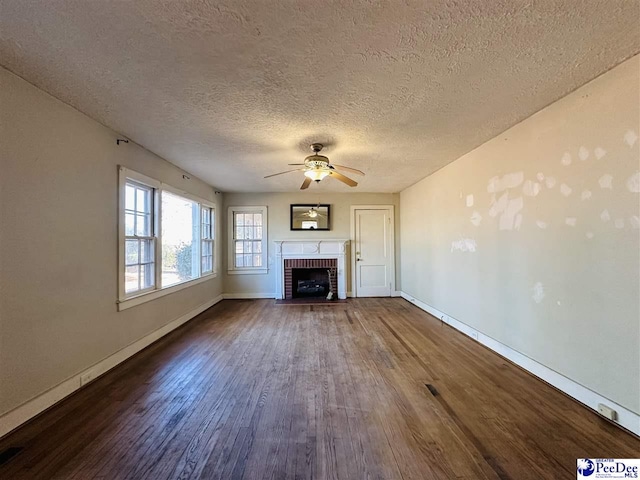 unfurnished living room featuring dark hardwood / wood-style flooring, a textured ceiling, a fireplace, and ceiling fan