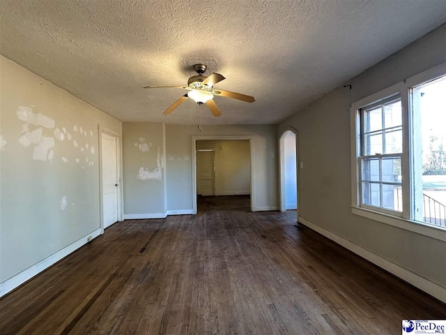 empty room with dark hardwood / wood-style floors, a textured ceiling, and ceiling fan