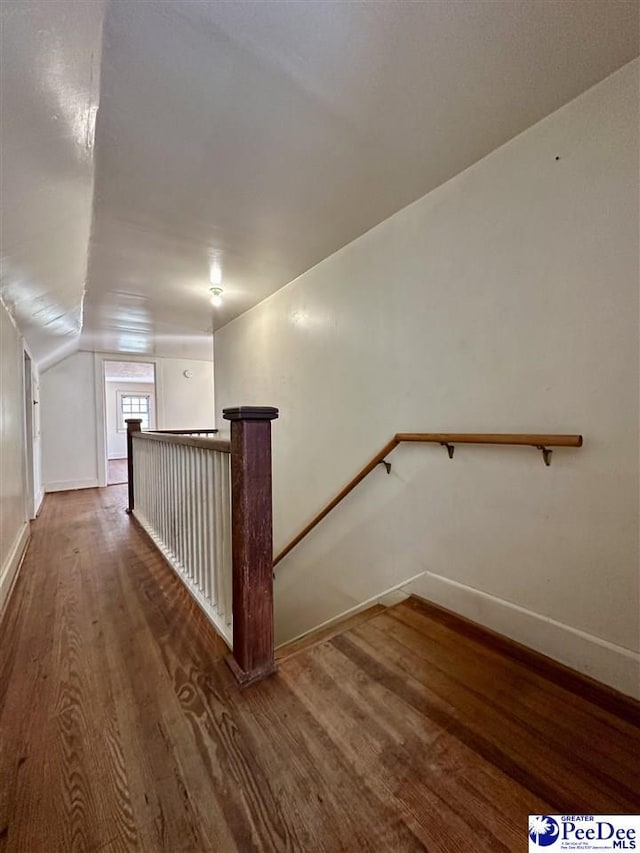 hallway featuring dark wood-type flooring and vaulted ceiling