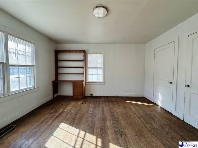 unfurnished bedroom featuring multiple windows and dark hardwood / wood-style floors