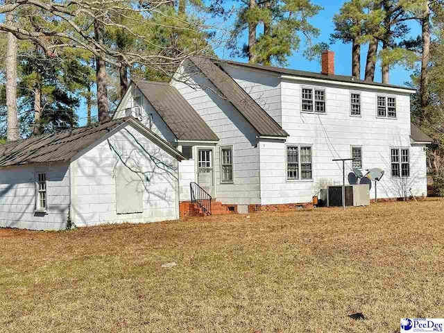 rear view of property featuring central AC and a lawn