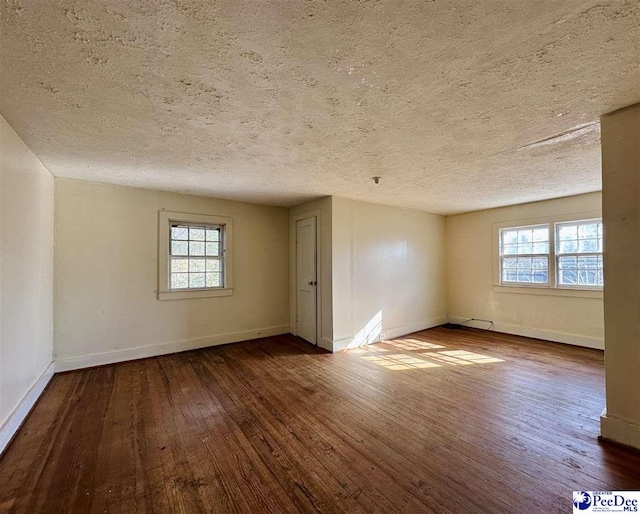 spare room featuring wood-type flooring, a textured ceiling, and plenty of natural light