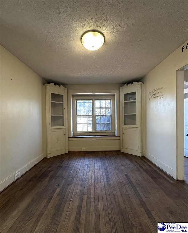 empty room featuring dark wood-type flooring and a textured ceiling