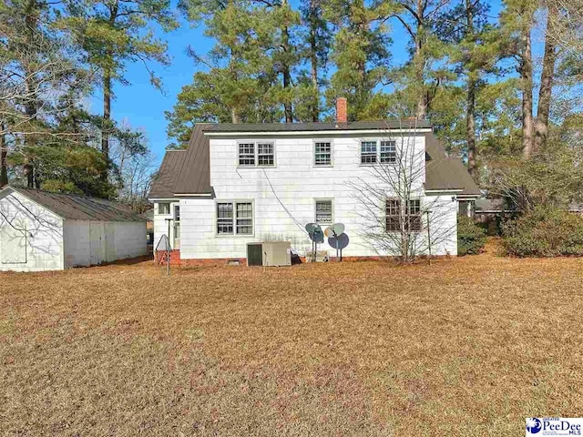 back of property with cooling unit, a shed, and a lawn