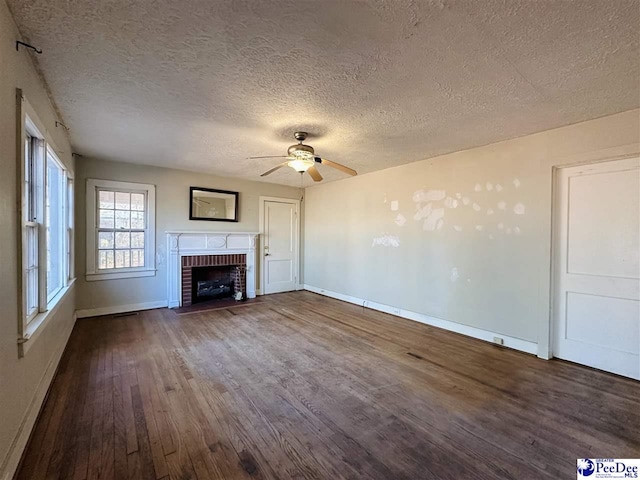 unfurnished living room with ceiling fan, hardwood / wood-style floors, a brick fireplace, and a textured ceiling