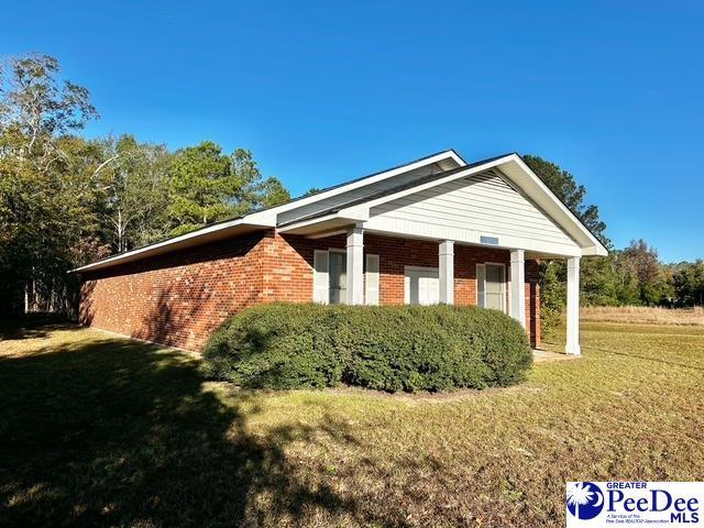 view of side of property featuring brick siding and a lawn