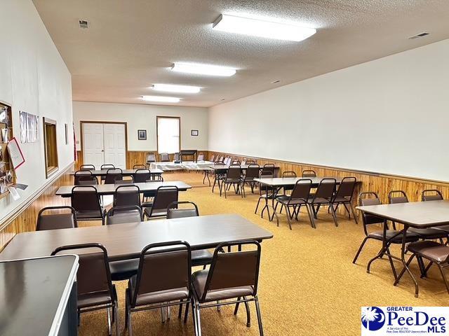 recreation room with a textured ceiling, wainscoting, and wooden walls