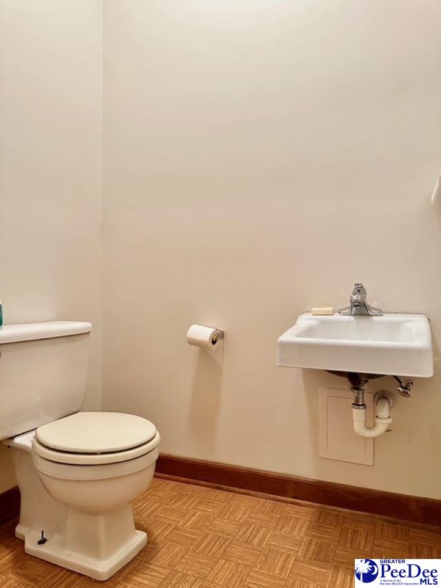 half bath featuring baseboards, a sink, and toilet