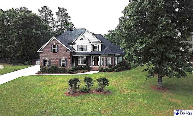 traditional home featuring a porch, brick siding, and a front yard