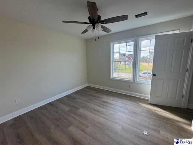 unfurnished room with baseboards, dark wood-style floors, and ceiling fan