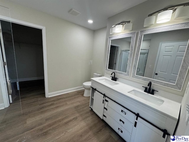 bathroom featuring toilet, wood finished floors, a sink, and baseboards