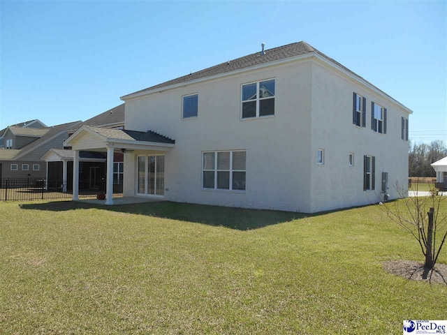 1081 Wessex Dr, Florence, SC 29501 - rear view of property featuring fence, stucco siding, a lawn, a ceiling fan, and a patio