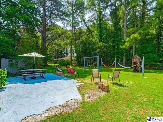 view of property's community featuring a playground, a lawn, and a patio area