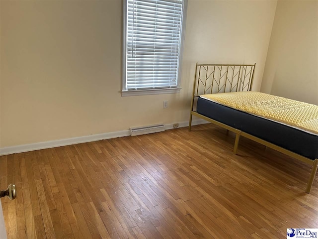 bedroom with visible vents, wood-type flooring, a baseboard radiator, and baseboards