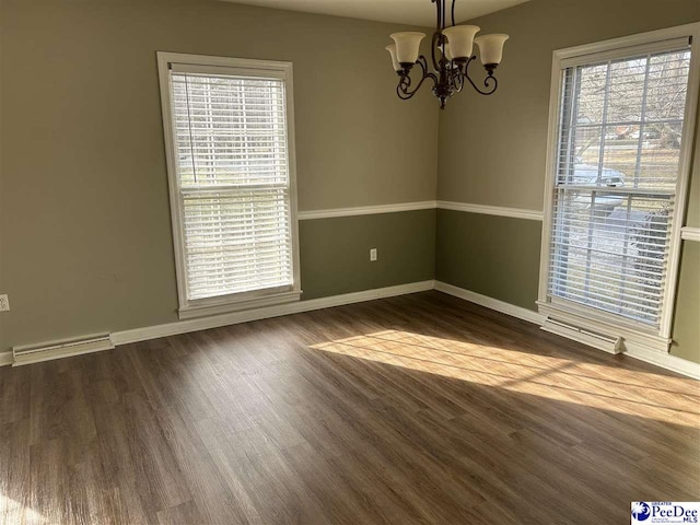 empty room with visible vents, a notable chandelier, baseboards, and wood finished floors