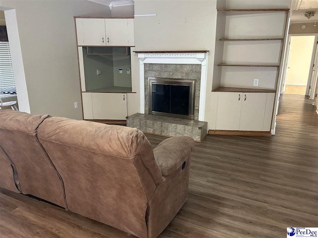 living room with a glass covered fireplace, dark wood finished floors, and built in features