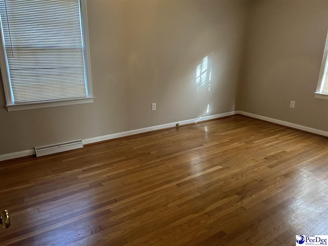 spare room featuring baseboards, baseboard heating, and hardwood / wood-style floors