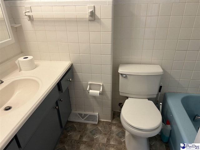 bathroom with toilet, visible vents, and tile walls