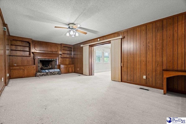 231 Timberlake Dr, Florence, SC 29501 - unfurnished living room with ceiling fan, wood walls, a brick fireplace, a textured ceiling, and light colored carpet