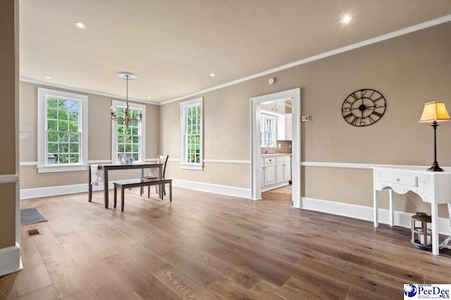 dining room with an inviting chandelier, ornamental molding, and wood-type flooring