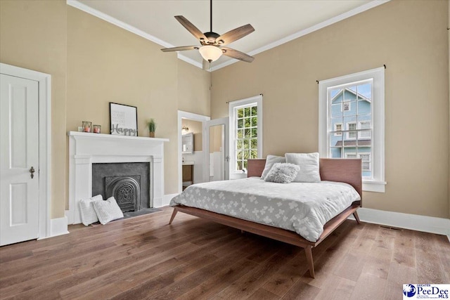 bedroom with hardwood / wood-style flooring, ornamental molding, connected bathroom, and ceiling fan