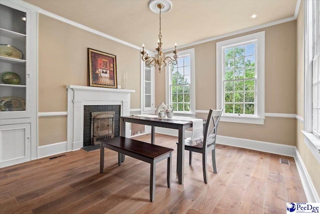 dining room featuring hardwood / wood-style flooring, ornamental molding, and a notable chandelier