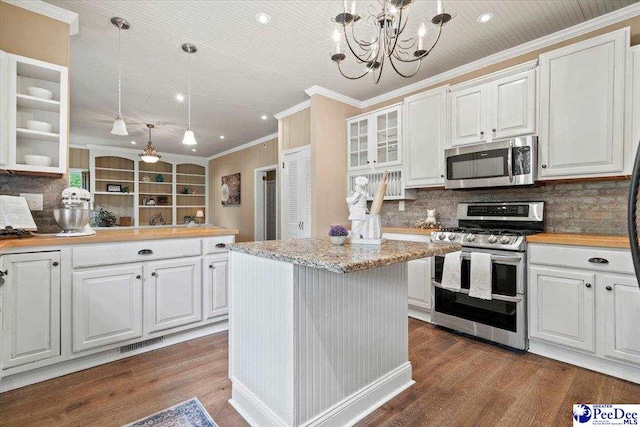 kitchen featuring white cabinetry, decorative light fixtures, a kitchen island, and appliances with stainless steel finishes