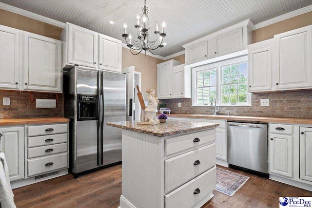 kitchen featuring white cabinetry, hanging light fixtures, crown molding, and appliances with stainless steel finishes