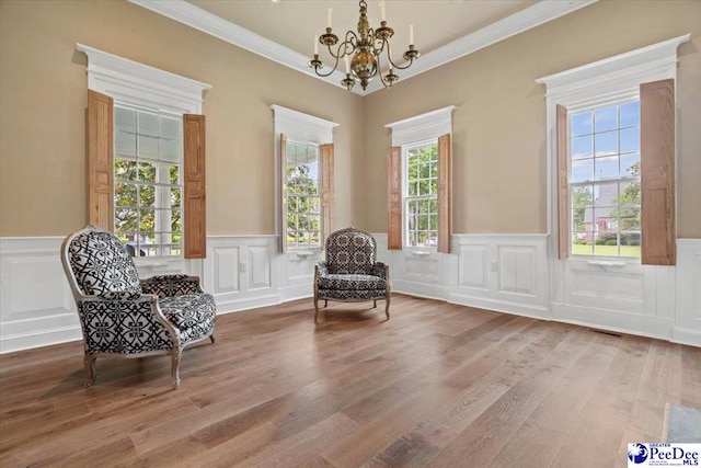 sitting room featuring an inviting chandelier, hardwood / wood-style flooring, and ornamental molding